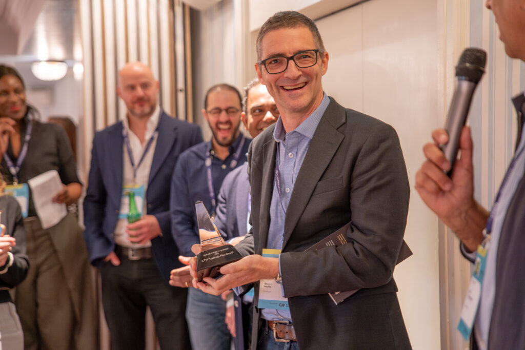 Stuart Mellis, CFO of Optalysys, smiling at the camera while holding the newly won trophy at Cambridge Tech Week.
