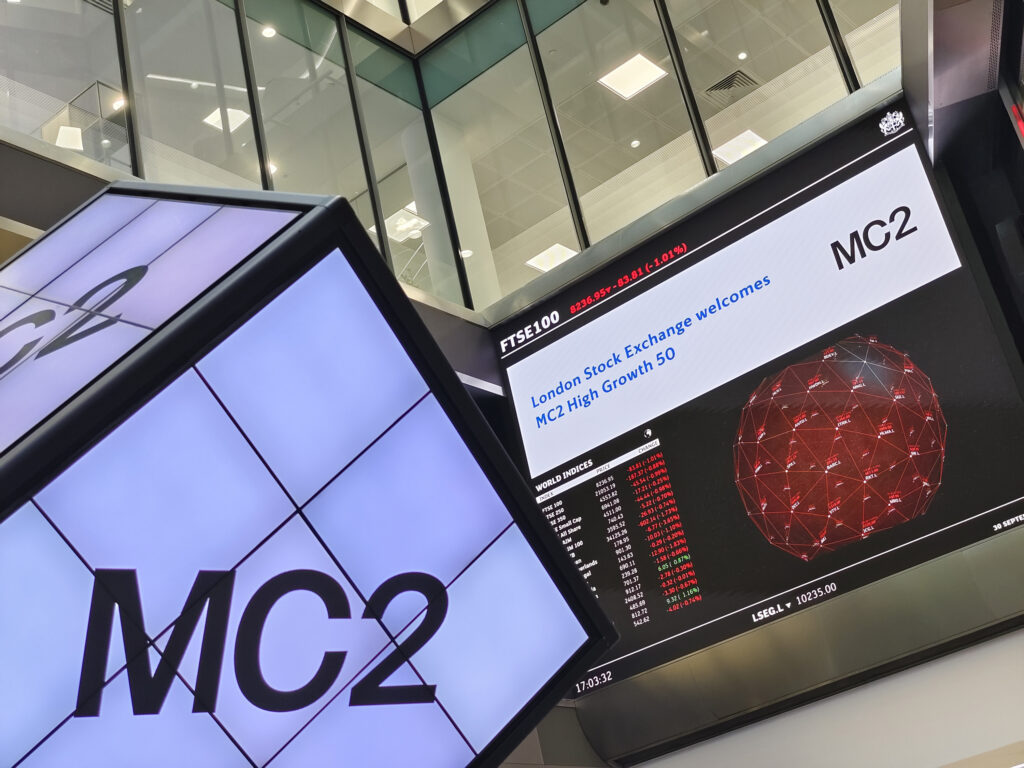 Photo of the London Stock Exchange with a live display reading 'London Stock Exchange welcomes MC2 High Growth 50'
